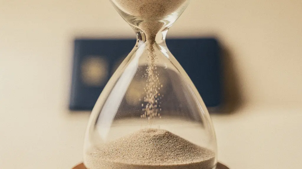 Vue macro d'un sablier en verre posé sur une surface claire, symbolisant l'importance de prévoir une marge de temps pour la validité du visa médical