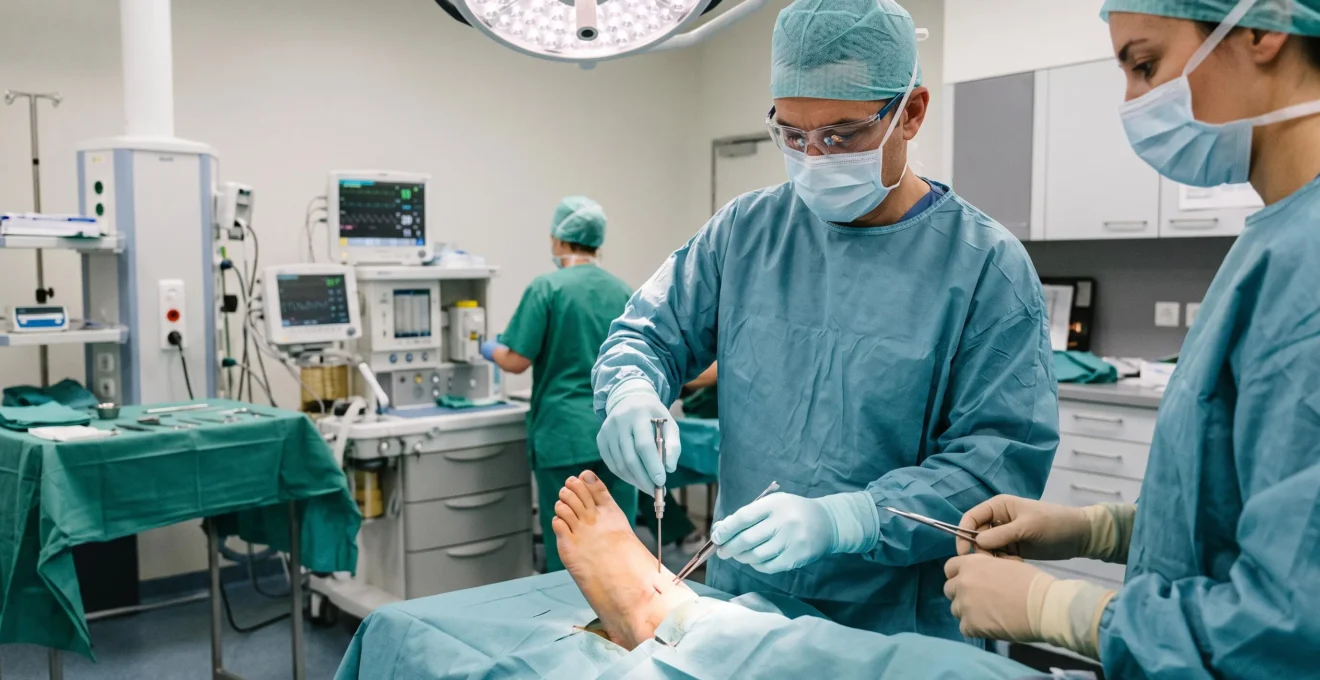 Chirurgien orthopédiste réalisant une intervention de chirurgie percutanée du pied au bloc opératoire avec instruments mini-invasifs