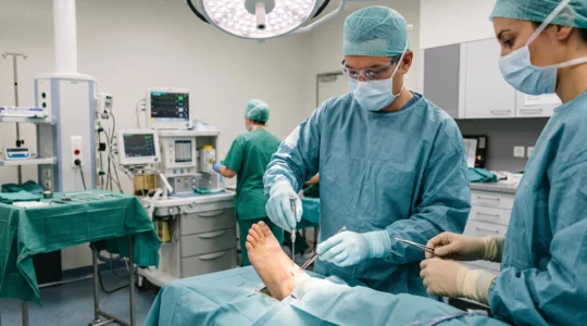 Chirurgien orthopédiste réalisant une intervention de chirurgie percutanée du pied au bloc opératoire avec instruments mini-invasifs